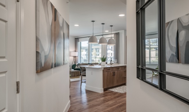 a hallway with wall art leading into a kitchen 