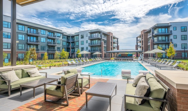 a lounge area with chairs, tables and couches in front of a swimming pool