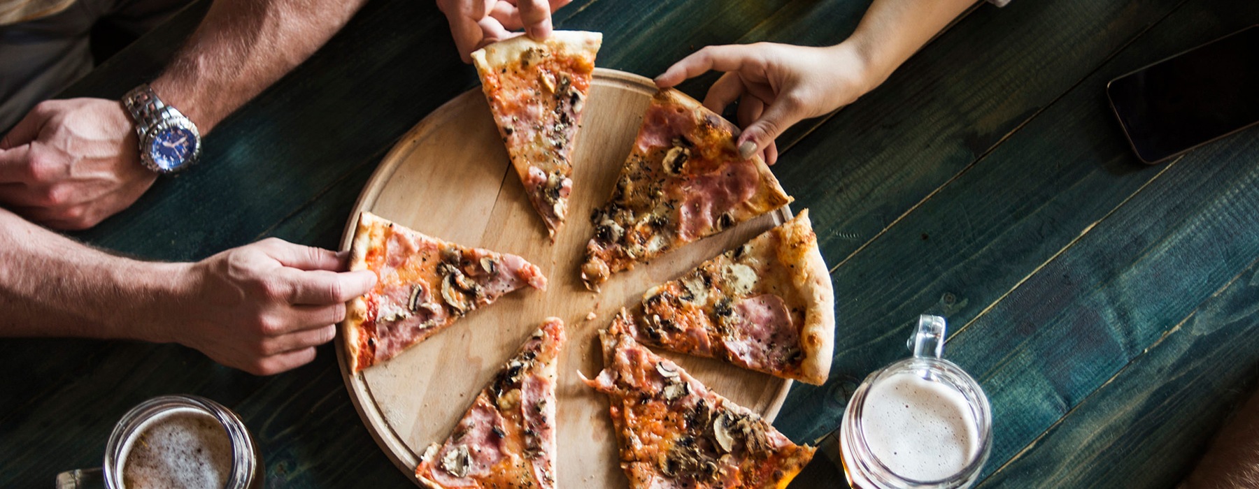 lifestyle image of hands pulling apart a large pizza